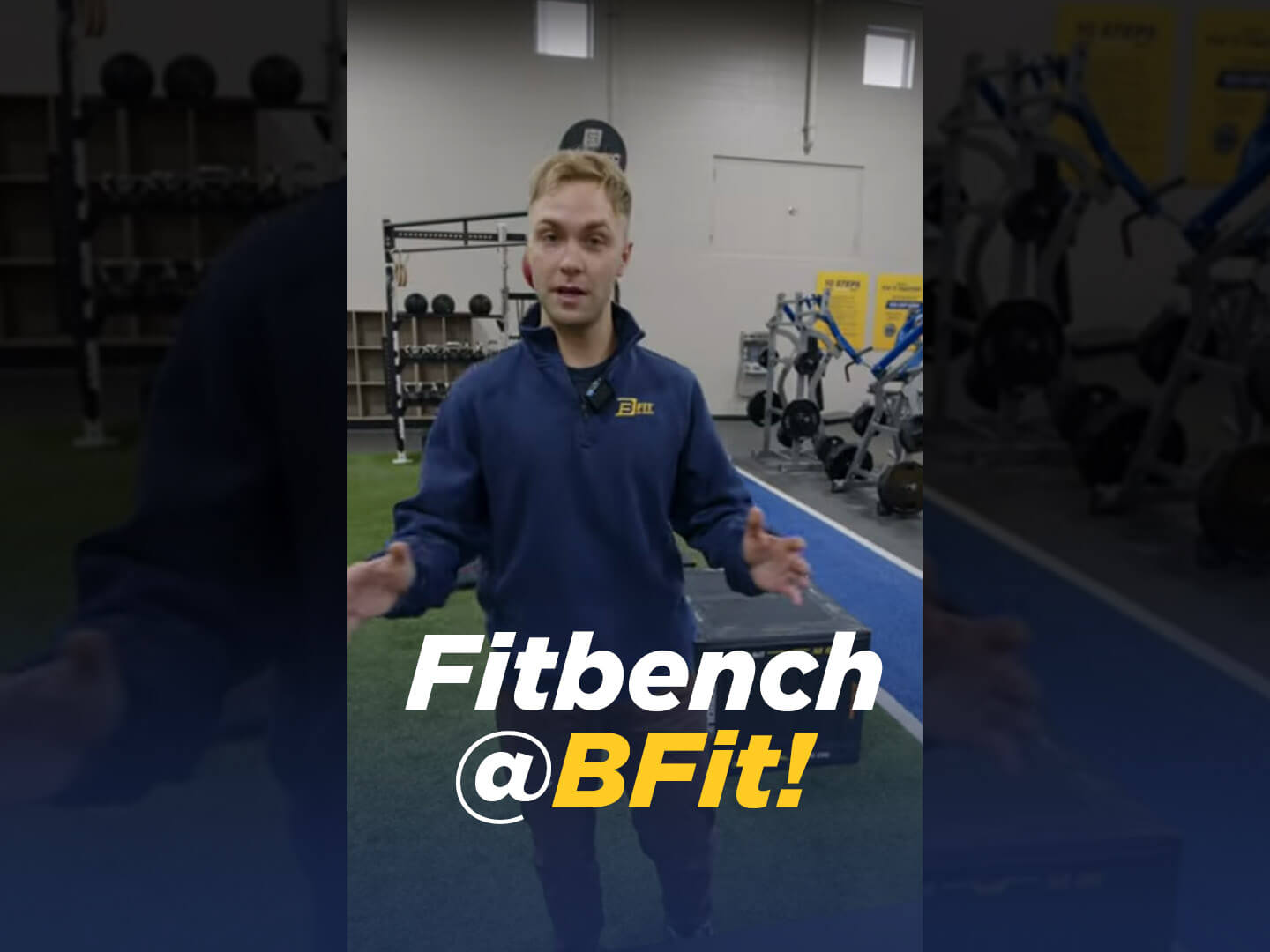 Trainer in gym demonstrating Fitbench equipment.