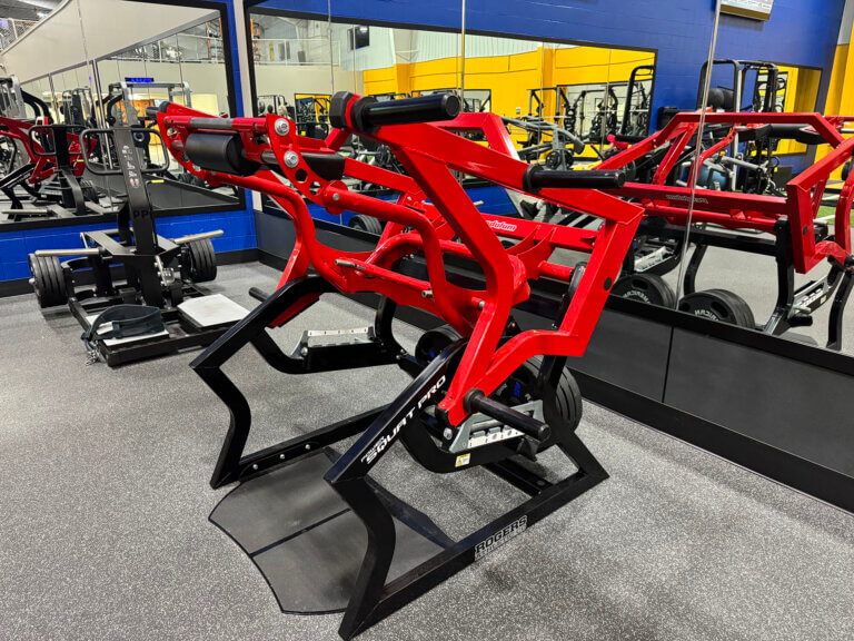Red squat machine in gym with mirrors.