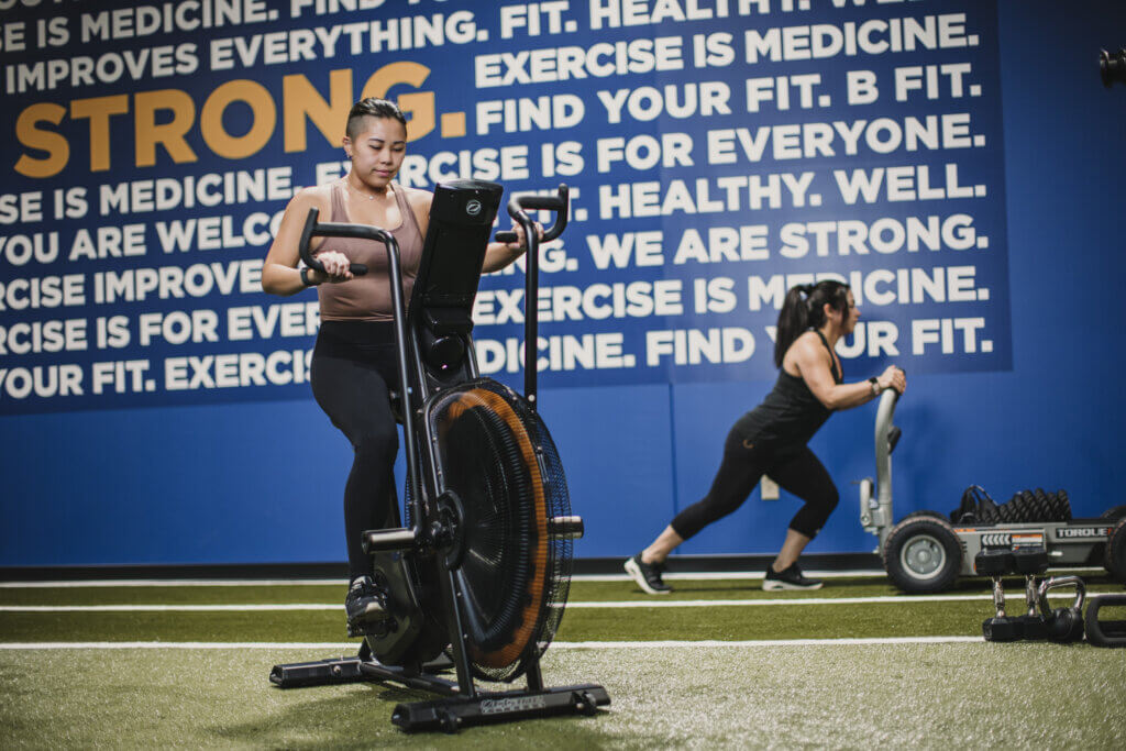 Women exercising on stationary bike and sled push