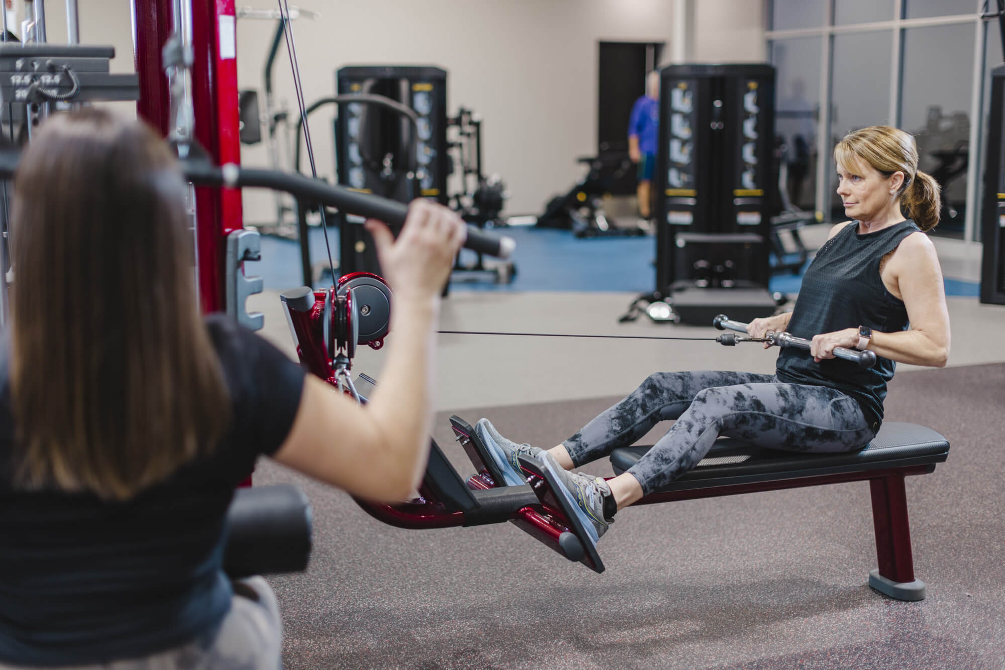 Two women using rowing machine at gym