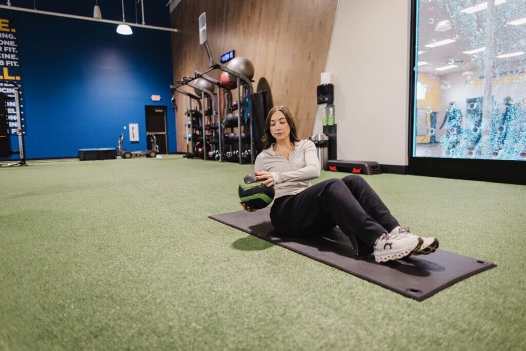 Woman exercising with medicine ball on mat