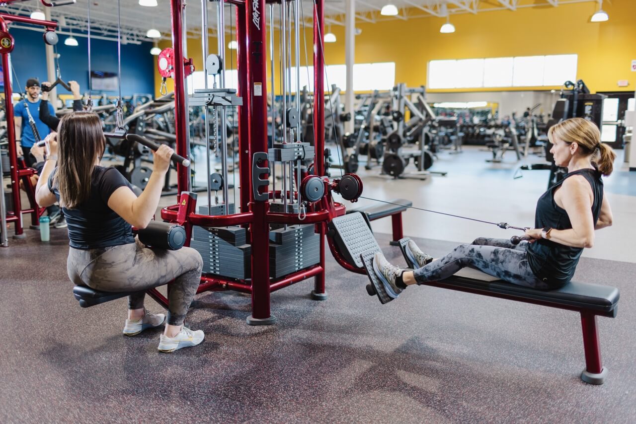 Two women using cable machines at gym